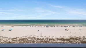 Ein Strand mit Sonnenschirmen und Liegestühlen, ein sandiger Uferstreifen und ein klarer Himmel.