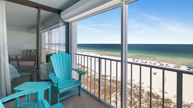 Ein Balkon mit Blick auf den Strand, einem Tisch und zwei Stühlen.