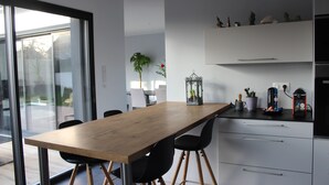 A modern kitchen with a wooden table, black chairs, and white cabinets.