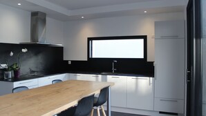 A modern kitchen with white cabinets, a wooden dining table, and black chairs.