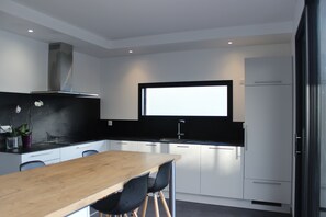 A modern kitchen with white cabinets, a wooden dining table, and black chairs.