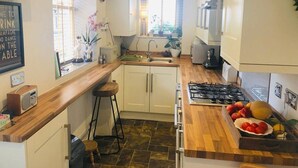 Una cucina compatta con piano di lavoro in legno, un fornello a gas, un lavello e una finestra con persiane.