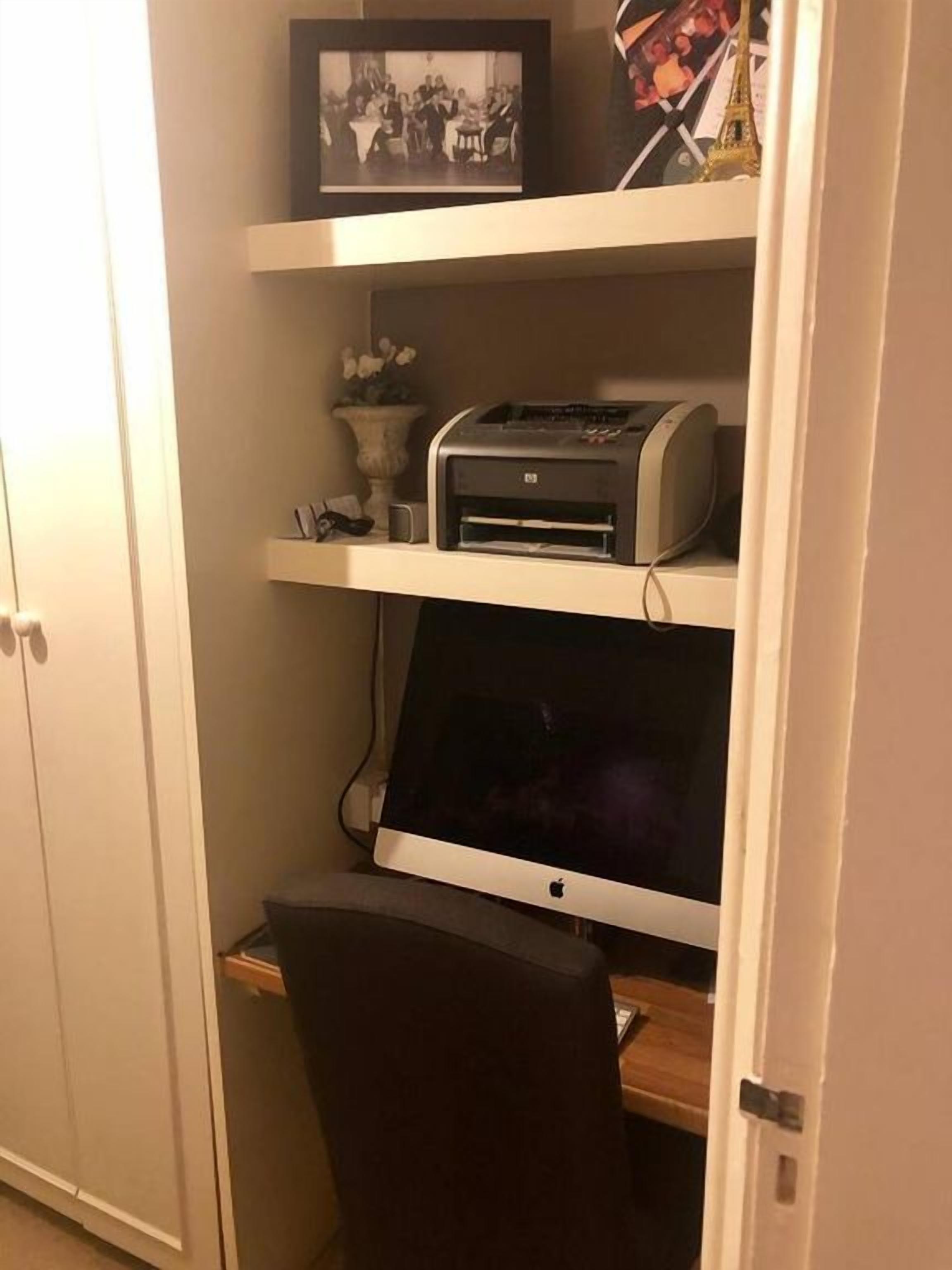Ein Home-Office-Arbeitsplatz mit Drucker, Bildschirm und Stuhl.