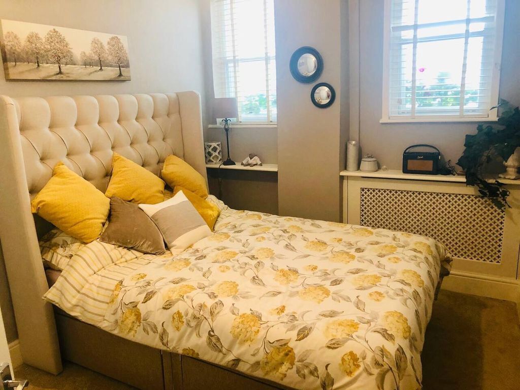 A bedroom with a tufted headboard, floral bedding, and a view of the city through windows.