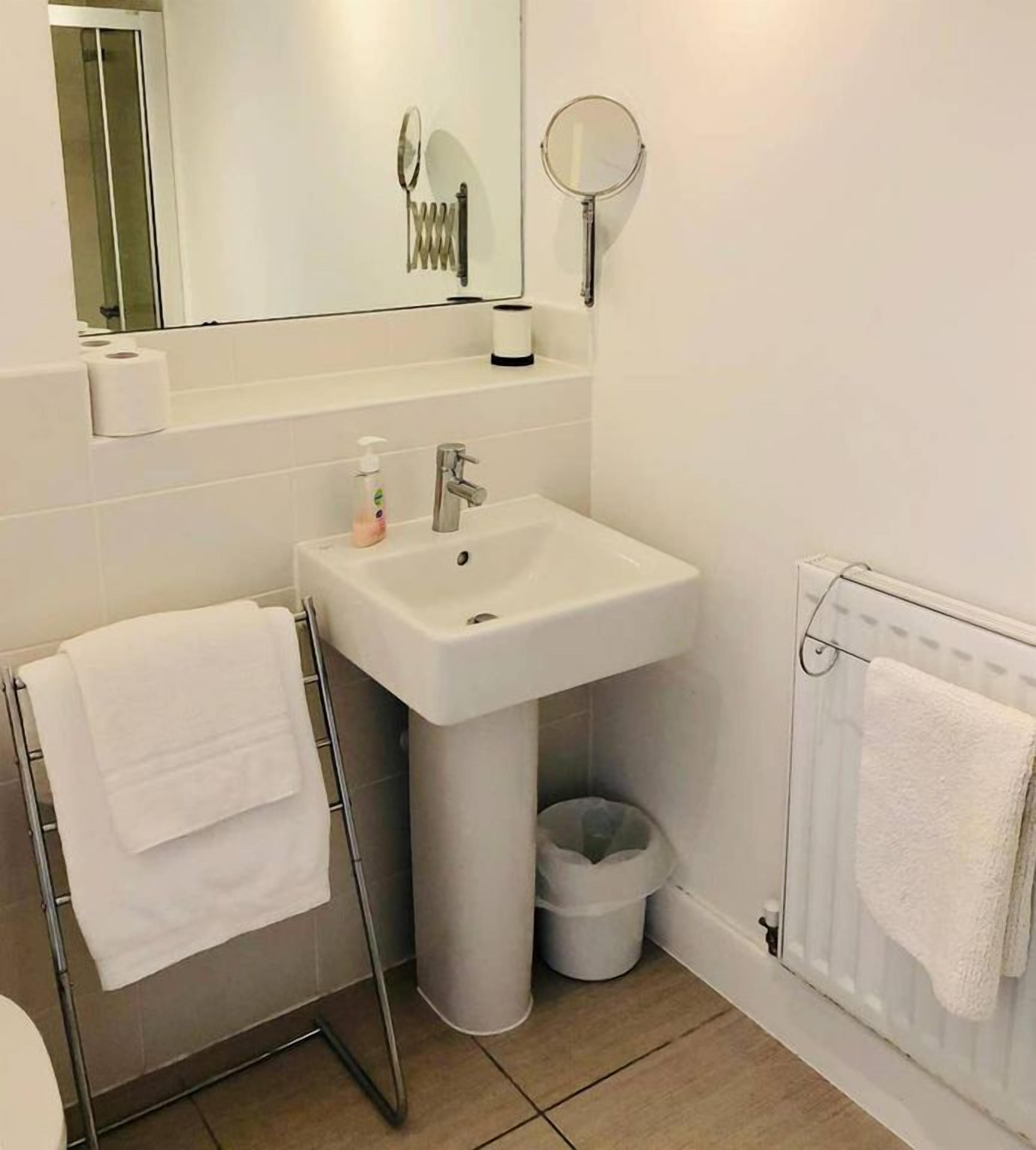 Une salle de bain avec un lavabo blanc, un miroir et un porte-serviettes.