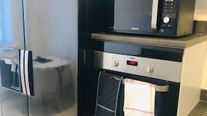 A modern kitchen with a black refrigerator, a microwave, and a built-in oven. - Canal Waterfront Townhouse (Leeds)