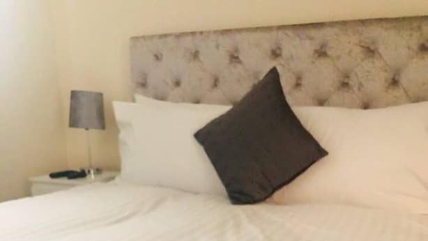 A neatly made bed with white linens and a single dark pillow. - Canal Waterfront Townhouse (Leeds)