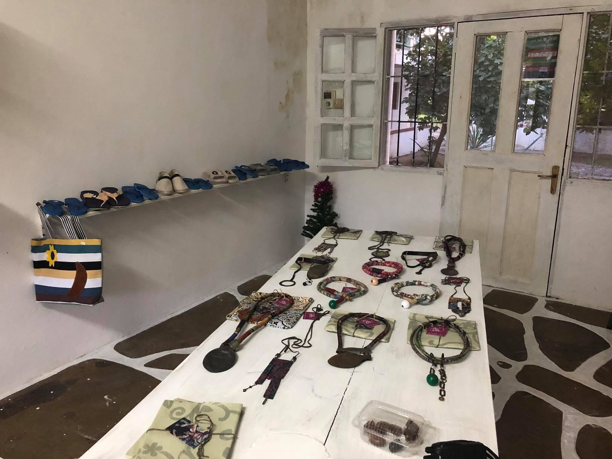 Ein Zimmer mit einem Tisch, auf dem verschiedene Schmuckstücke liegen, einem Schuhregal und einer Tür mit Fenster.