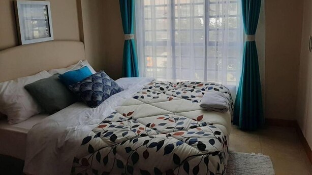 Quarto com duas camas, uma janela com cortinas e um quadro na parede.