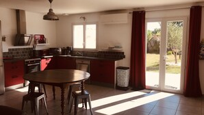 A kitchen with a dining table, chairs, a sink, and a window with curtains. - Holiday villa with pool in Vallon Pont d'Arc, near the Ardèche river (Vallon-Pont-d'Arc)
