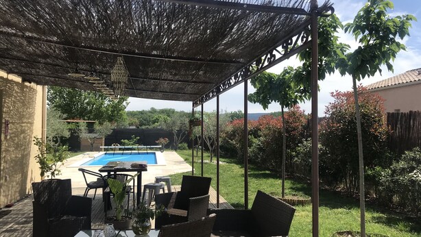 An outdoor patio with wicker furniture, a glass table, and a pool in the background. - Holiday villa with pool in Vallon Pont d'Arc, near the Ardèche river (Vallon-Pont-d'Arc)