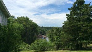 A grassy yard with trees and a dock extending into a body of water. - Family Lake View Home - with Dock Access  (Sunrise Beach)