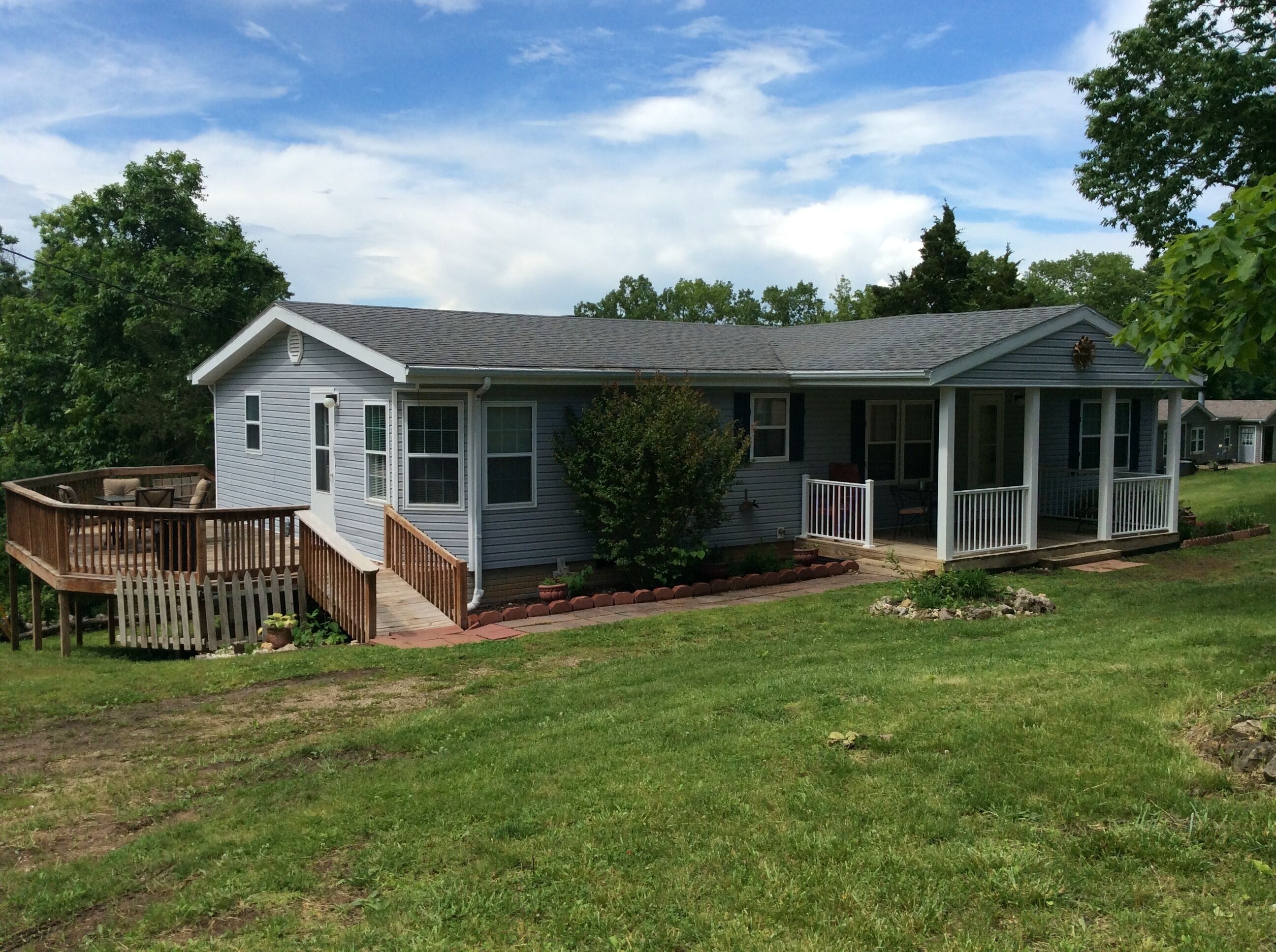 A single-story house with a covered porch, a deck, and a small garden area.