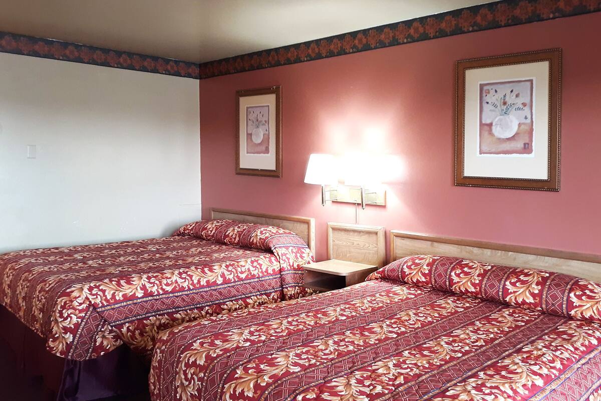 Une chambre d’hôtel avec deux lits, une table de chevet et deux lampes fixées au mur.