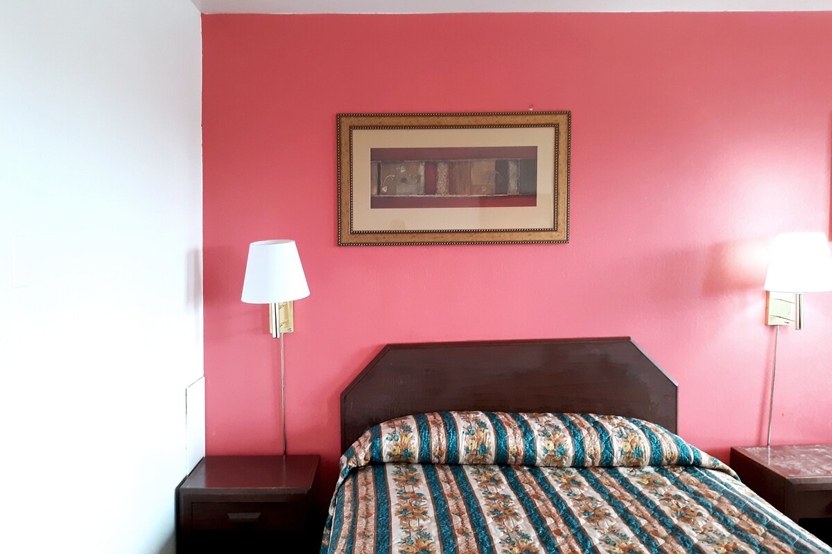 A room with a bed, two bedside tables, and a framed picture on the wall.