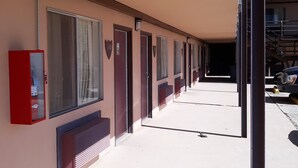 Una fila de habitaciones de hotel con grandes ventanales y una caja roja de alarma contra incendios en la pared.