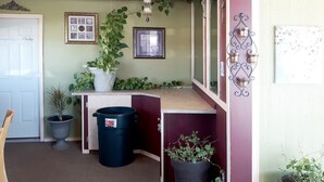 Un pasillo con una puerta que dice 'Solo empleados', una planta en maceta, un cubo de basura y una lámpara fijada a la pared.