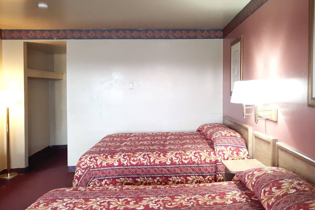 Une chambre d’hôtel avec deux lits, une table de chevet, une lampe et un miroir au mur.