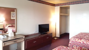 A hotel room with a bed, a TV on a wooden dresser, a bedside table with a lamp, and a mirror. - OYO Hotel Kings at Clovis (Clovis)