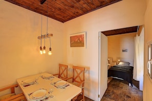 A dining area with a wooden table set for four, a wooden chair, and a hanging light fixture. - Living in a stylishly renovated town house in Santa Cruz de la Palma (santa cruz de la palma)