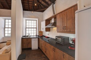 A compact kitchen with wooden cabinets, a built-in microwave, and a stove. - Living in a stylishly renovated town house in Santa Cruz de la Palma (santa cruz de la palma)