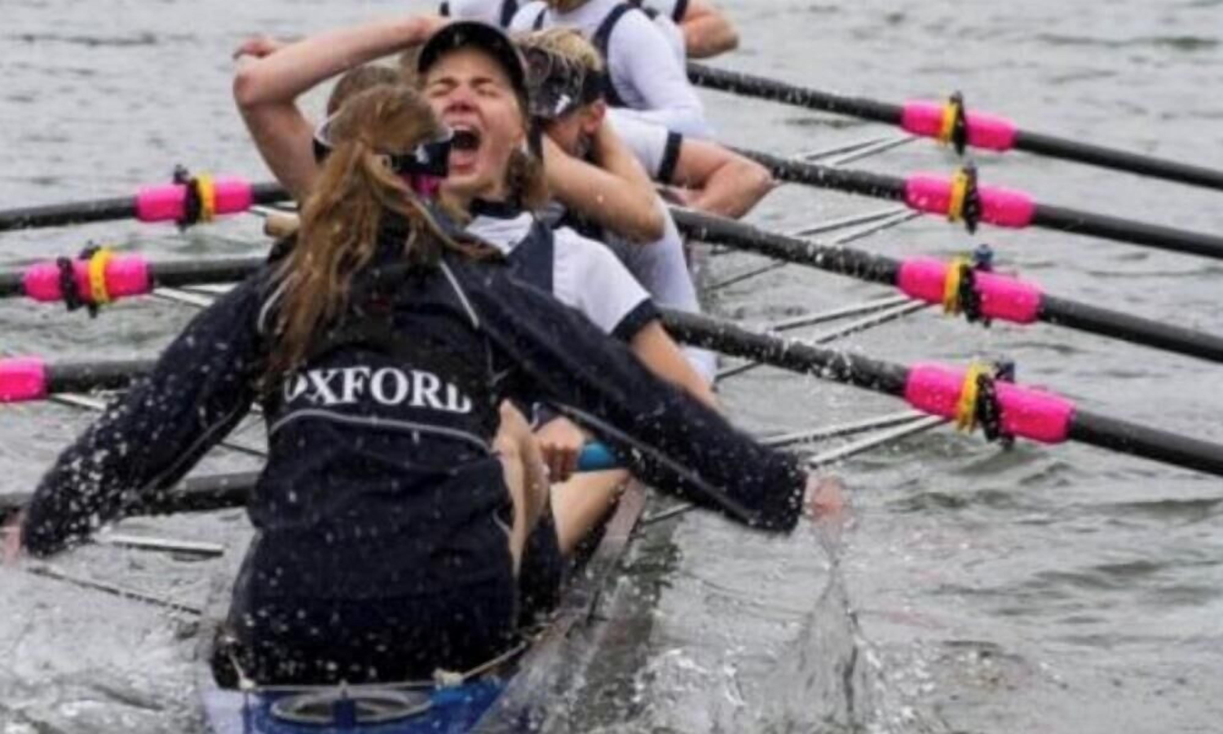 Un equipo de remo en un bote, con remos y usando uniformes iguales.