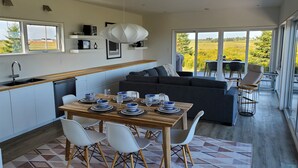 Et moderne køkken med spiseplads, en sofa og udsigt til det fri.