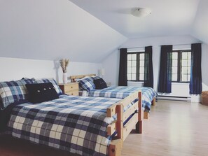 Een slaapkamer met twee houten bedden, een nachtkastje, een raam met gordijnen en een plafondlamp.
