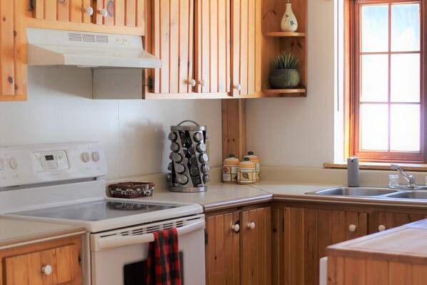 Una cocina con armarios de madera, estufa blanca y una ventana con persianas.