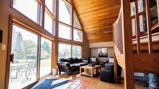 Amplia sala de estar con un ventanal, techo de madera y vistas al exterior.