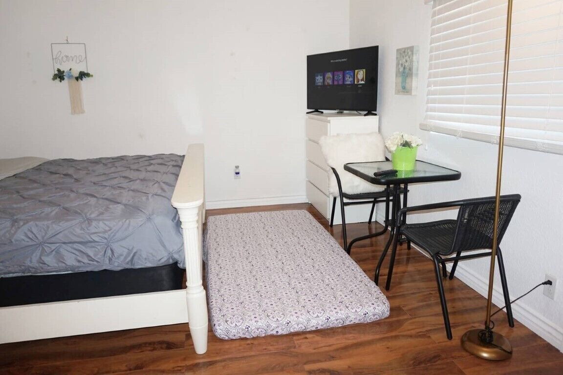 A small, tidy room with a bed, a desk, a chair, and a television.