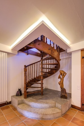 A wooden spiral staircase with a wooden handrail and a decorative wooden sculpture at the bottom.