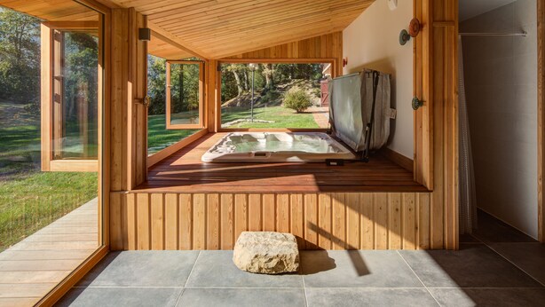 A wooden cabin with a hot tub, a stone centerpiece, and a view of a garden. - Architect's house not overlooked in the Ossau valley, spa & sauna, 7000m2 park (Béost)