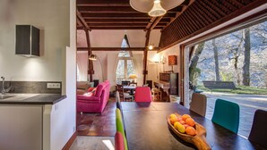 A modern kitchen with a built-in dishwasher, a dining area with a wooden table and chairs, and a large window offering a view of the outdoors. - Architect's house not overlooked in the Ossau valley, spa & sauna, 7000m2 park (Béost)