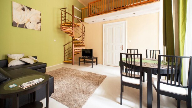 A living room with a staircase, a sofa, a coffee table, and a dining table with chairs.