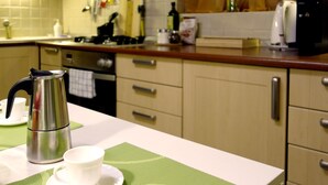 A kitchen with a coffee maker, a cup, and a saucer on the counter.