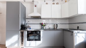 Une cuisine moderne avec des armoires blanches, un four encastré et une hotte de cuisinière en acier inoxydable.