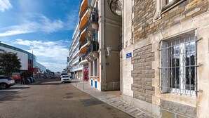 Une vue de rue montrant un bâtiment avec une façade en pierre, un portail en métal et un panneau indiquant une zone interdite d’accès.