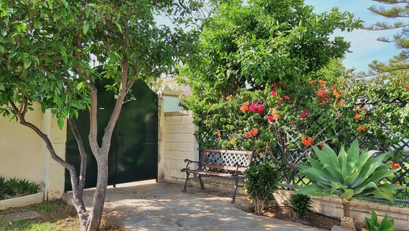 A courtyard with a bench, a green gate, and flowering plants.