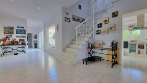 Een ruime binnenruimte met een trap, kunstwerken aan de muur en een keuken.