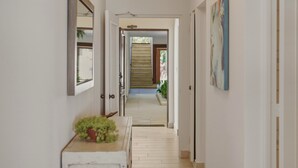 A hallway with a potted plant, a mirror, and a painting on the wall. - Oceanfront Condo, King Bed, Pool | Unit 110 (Cabarete)