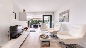 A modern living room with a flat-screen TV, white leather chairs, a coffee table, and a bookshelf. - La détente 3149 villa (Les Issambres)
