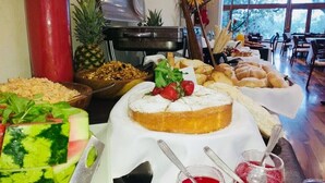 A buffet with various food items including a watermelon salad, a fruit bowl, and a variety of breads and pastries. - Los Espinillos Hotel & Spa (Villa Carlos Paz)