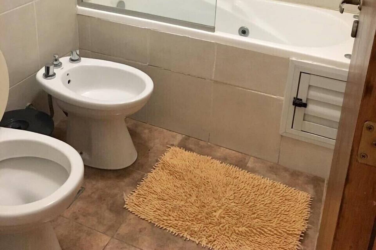 Een badkamer met een bad, een toilet en een hygiëneschuimer.