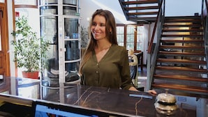 A woman standing at a kitchen counter with a marble top, a potted plant, and a staircase in the background. - Los Espinillos Hotel & Spa (Villa Carlos Paz)