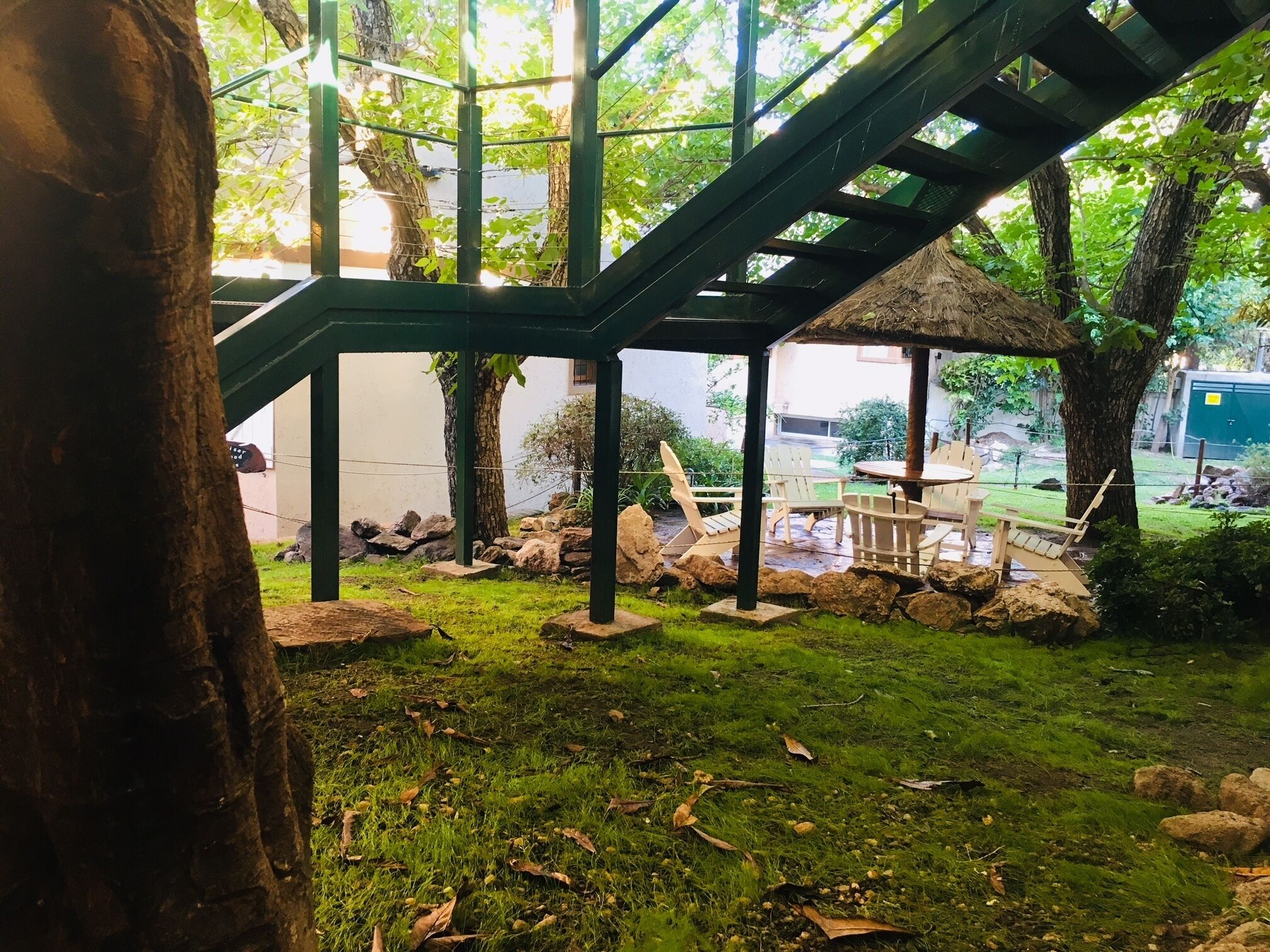 Un espacio al aire libre techado con paja, con asientos y un muro de piedra.