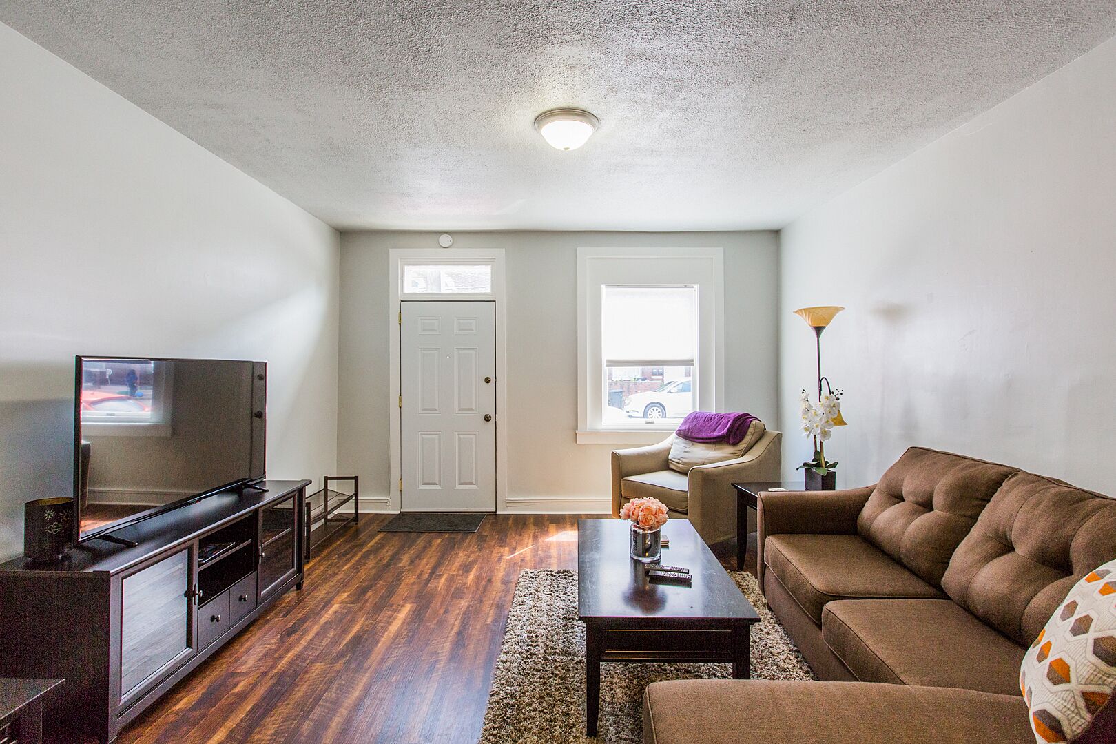 A living room with a TV, sofa, coffee table, and a door leading to another room.