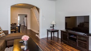 Un salon comprenant un canapé, une table basse, un téléviseur et un escalier menant à une autre pièce.