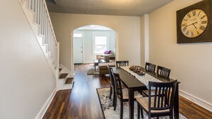 Un espace repas comprenant une longue table, des chaises et une horloge fixée au mur.