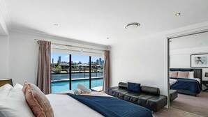 Een moderne hotelkamer met een groot bed, een zithoek en uitzicht op een stadsbeeld en water.
